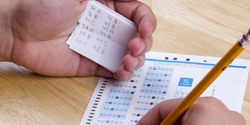 أشخاص يتسلقون جدار المدرسة لتمرير أوراق الغش للطلاب خلال الامتحان في الهند الغش